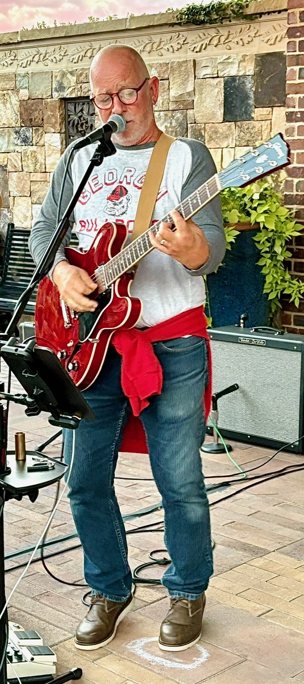 Danny Dukes performing outdoors with a red electric guitar
